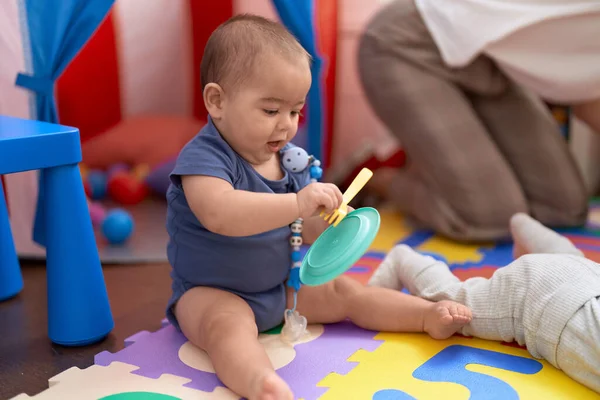 愛らしい中国の幼児遊びとともに皿やフォークおもちゃに座っています床に幼稚園 — ストック写真