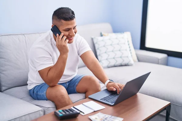 Genç Latin Adam Akıllı Telefonda Dizüstü Bilgisayar Kullanarak Konuşuyor — Stok fotoğraf