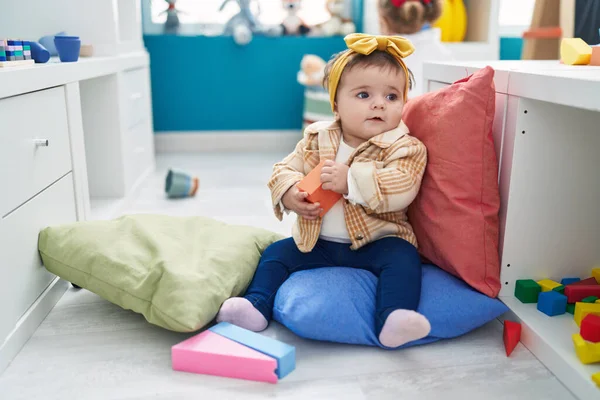 可爱的金发碧眼的幼儿在幼儿园抱着木制玩具坐在地板上 — 图库照片
