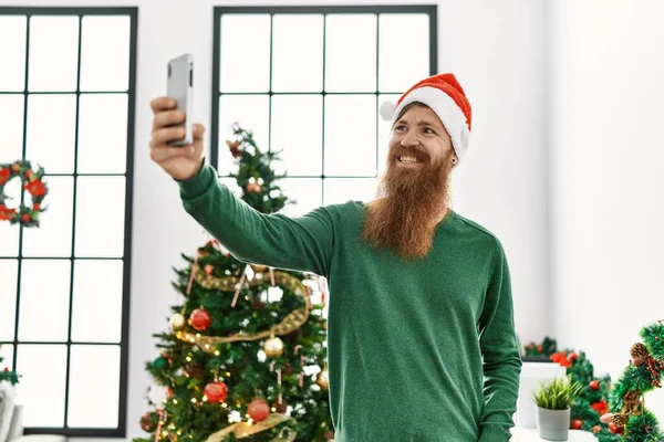 Молодой Рыжий Мужчина Делает Селфи Смартфона Стоящего Рождественской Елки Дома — стоковое фото