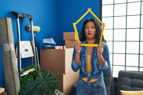Young asian woman moving to a new home in shock face, looking skeptical and sarcastic, surprised with open mouth 
