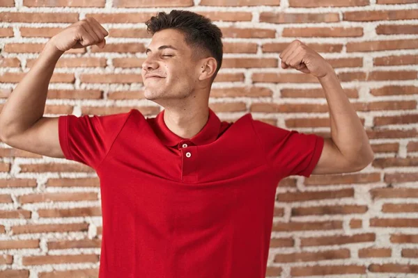 Young Hispanic Man Standing Bricks Wall Showing Arms Muscles Smiling —  Fotos de Stock
