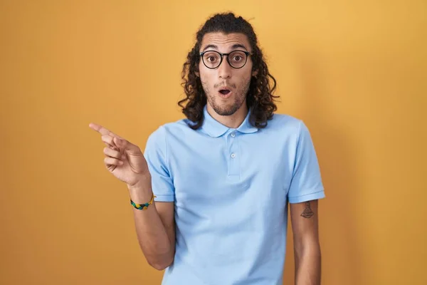 Young Hispanic Man Standing Yellow Background Surprised Pointing Finger Side — Stock Photo, Image