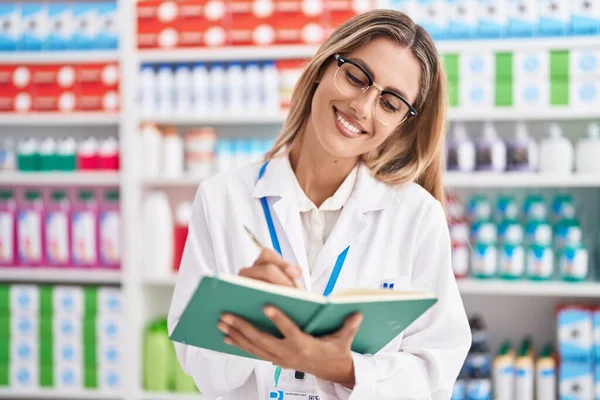 Young Blonde Woman Pharmacist Writing Document Pharmacy — Zdjęcie stockowe