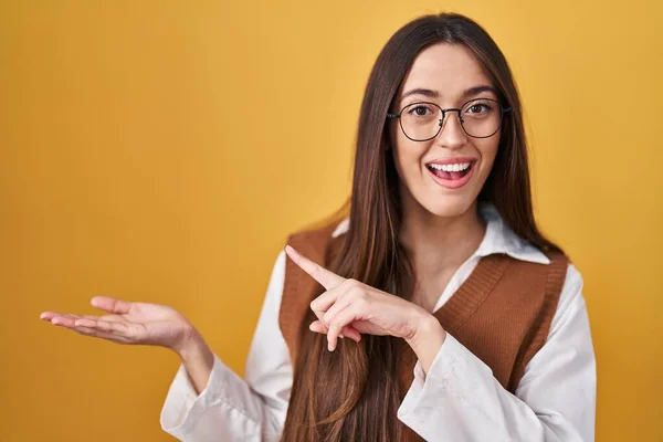 Young Brunette Woman Standing Yellow Background Wearing Glasses Amazed Smiling — Fotografia de Stock