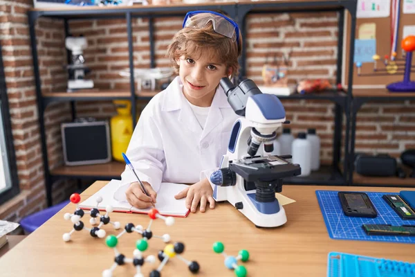 Adorable Kaukaski Chłopiec Student Pomocą Mikroskopu Pisanie Notatniku Klasie — Zdjęcie stockowe