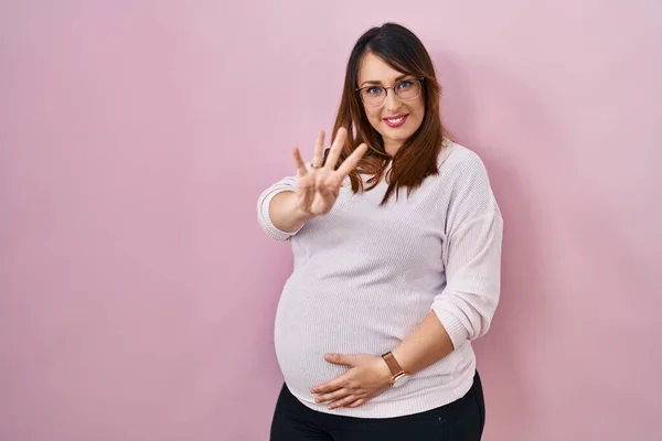Kobieta Ciąży Stoi Nad Różowym Tle Pokazując Wskazując Palcem Numer — Zdjęcie stockowe