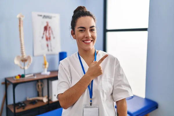 Young Hispanic Woman Working Rehabilitation Clinic Cheerful Smile Face Pointing — Fotografia de Stock