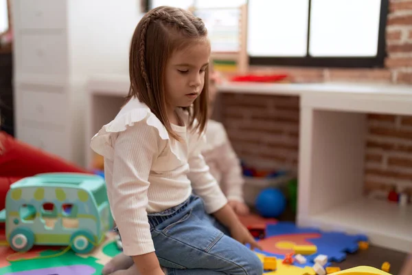 可爱的惊慌失措的女孩坐在地板上 带着轻松的表情在幼儿园里 — 图库照片
