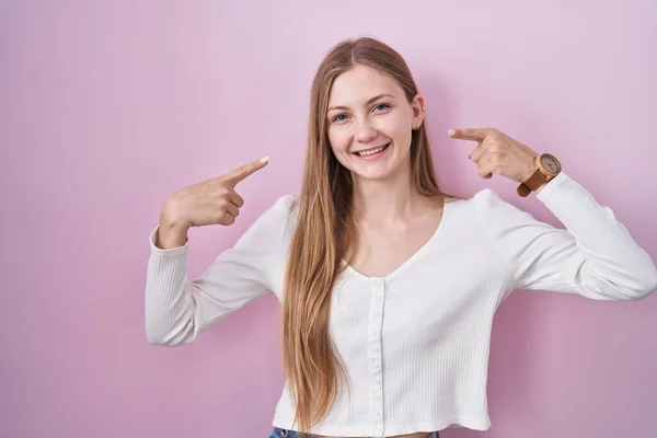 Mladá Běloška Stojí Nad Růžovým Pozadím Vesele Usmívá Ukazuje Ukazuje — Stock fotografie