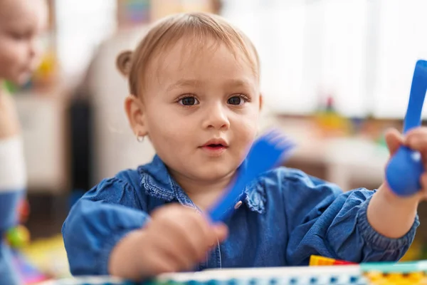 stock image Adorable hispanic girl sitting on table holding fork and spoon at kindergarten