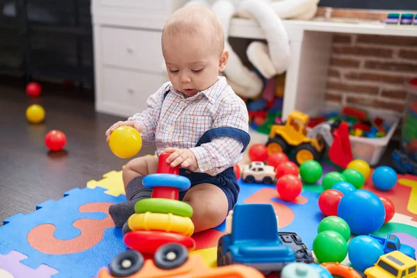 幼稚園の床に座っているボールやフープで遊ぶ愛らしい白人の赤ちゃん — ストック写真
