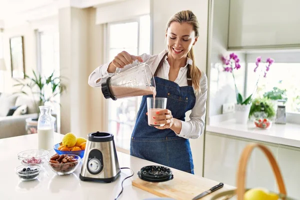 Young Blonde Woman Smiling Confident Pouring Smoothie Glass Kitchen — Stock Photo, Image