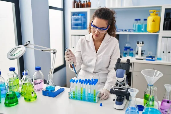 Genç ve güzel İspanyol bilim kadını laboratuardaki test tüplerine sıvı döküyor.