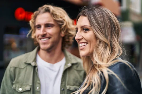 Erkek ve kadın bir arada durarak gülümsüyor.