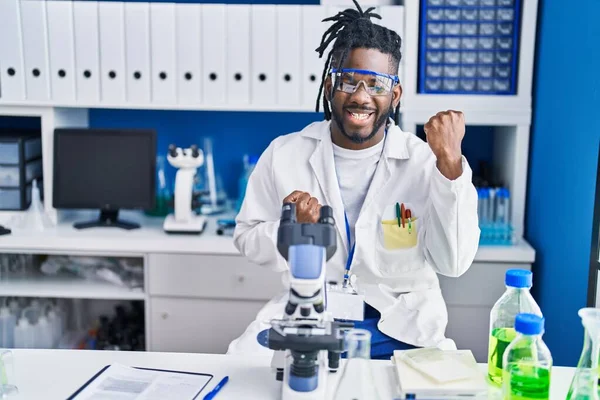 科学研究所で働いているアフリカ人の男は驚いて 腕を上げて目を閉じて成功したことに驚いています — ストック写真