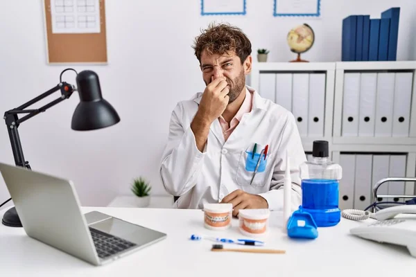 Young Hispanic Dentist Man Working Medical Clinic Smelling Something Stinky — Stock Photo, Image