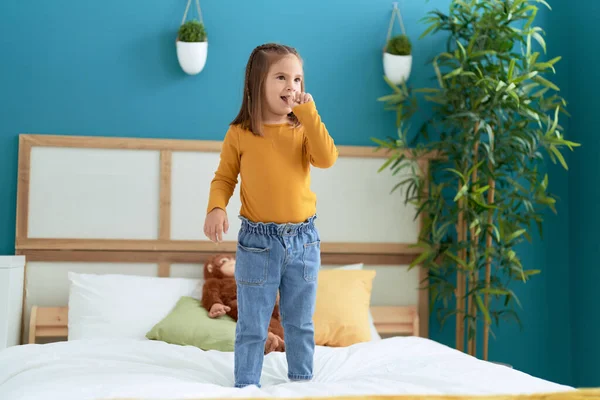 可爱的惊慌失措的女孩自信地站在床上的卧室里 — 图库照片