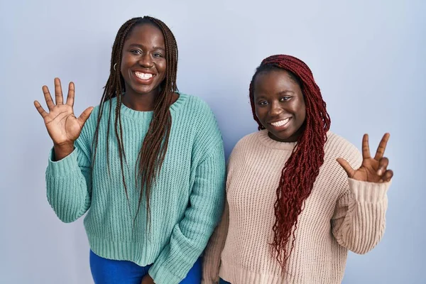 Two African Woman Standing Blue Background Showing Pointing Fingers Number — ストック写真
