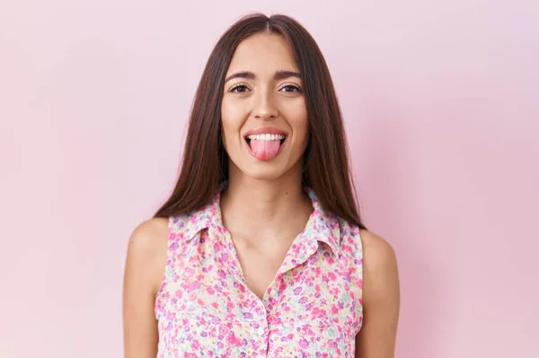 Nuori Latino Nainen Pitkät Hiukset Seisoo Vaaleanpunainen Tausta Törröttää Kielen — kuvapankkivalokuva