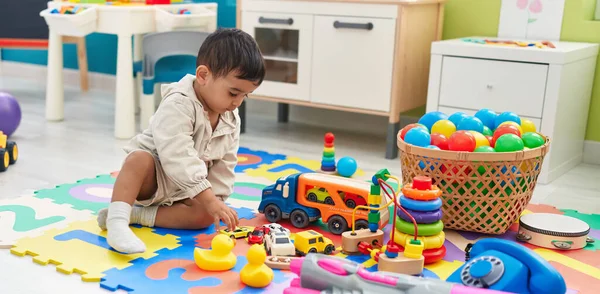 愛らしいヒスパニック幼児遊びとともに車のおもちゃ座っています床に幼稚園 — ストック写真