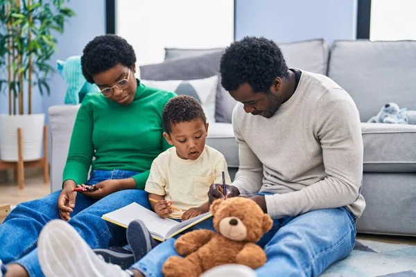 African american family drawing on notebook sitting on floor at home