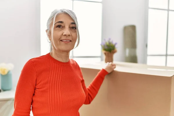 Middle age grey-haired woman smiling confident standing at new home