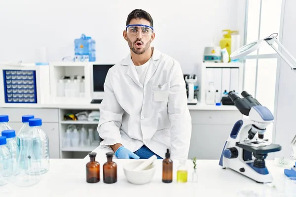 Young Hispanic Man Working Scientist Laboratory Scared Amazed Open Mouth — Stockfoto