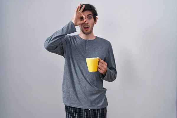 Young Hispanic Man Wearing Pajama Drinking Cup Coffee Doing Gesture — Stock fotografie