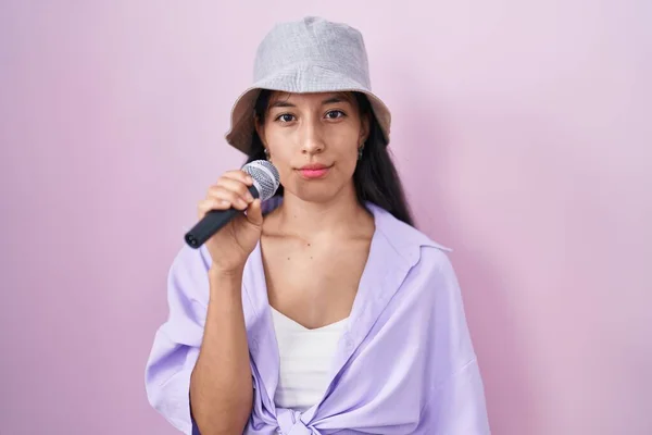 Young Hispanic Woman Singing Song Using Microphone Pink Background Thinking — Stock Photo, Image