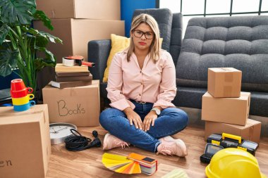 Young hispanic woman moving to a new home sitting on the floor depressed and worry for distress, crying angry and afraid. sad expression. 