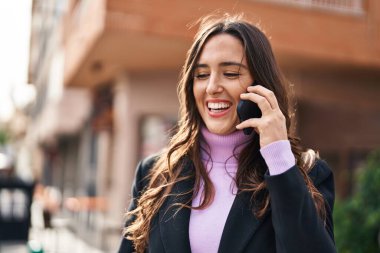 Genç İspanyol kadın gülümsüyor. Kendine güveniyor. Akıllı telefondan konuşuyor.