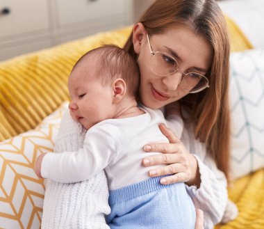 Anne ve oğul evdeki kanepede oturup birbirlerine sarılıyorlar.