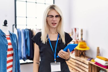 Perakende mağazasında yönetici olarak çalışan genç sarışın kadın kameraya seksi bir ifadeyle bakıyor, neşeli ve mutlu bir yüzle.. 