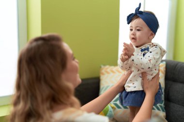 Woman and toddler standing on sofa playing at home