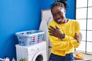 African american woman hugging himself hanging clothes on clothesline at laundry room