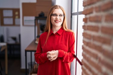Young redhead woman business worker smiling confident standing at office