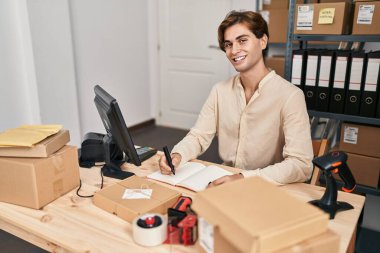Young caucasian man ecommerce business worker writing on notebook at office