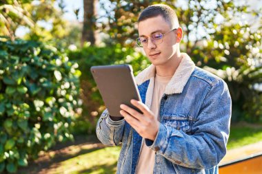 Genç İspanyol bir adam parkta dokunmatik bir yüz ifadesi kullanıyor.