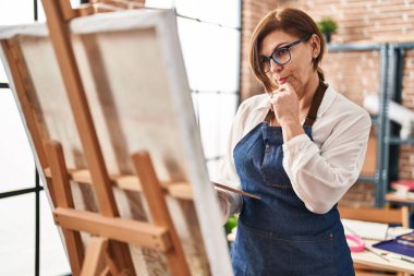 Resim stüdyosunda resim çizen orta yaşlı kadın sanatçı.