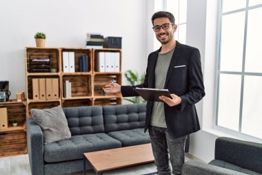 Young hispanic man having psychology session holding checklist welcoming patient at clinic