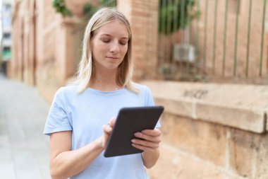 Young blonde woman using touchpad at street