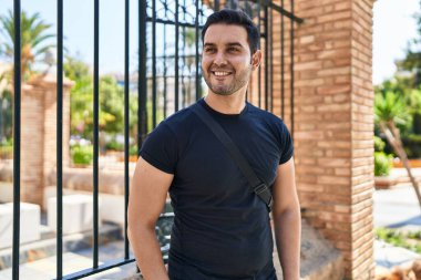 Sokakta kendinden emin gülümseyen İspanyol genç adam.