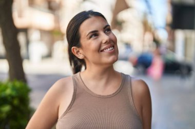 Young beautiful hispanic woman smiling confident looking to the side at street