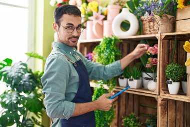 Çiçekçide dokunmatik ped kullanarak gülümseyen İspanyol çiçekçi.