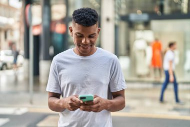 Sokakta akıllı telefon kullanan, kendine güvenen genç Latin adam.