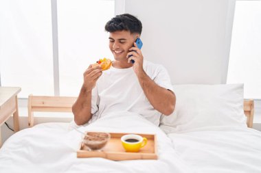 Genç İspanyol adam kahvaltısını yapıyor. Akıllı telefondan konuşuyor.