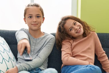 Two kids watching tv sitting on sofa at home