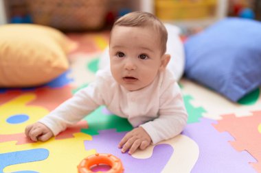 Anaokulunda yerde yatan sevimli çocuk.