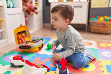 Adorable hispanic boy playing with supermarket game at kindergarten